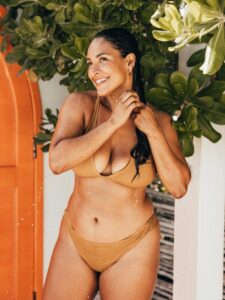 Woman rinsing off in an outdoor shower wearing a bathing suit, Carmel, IN