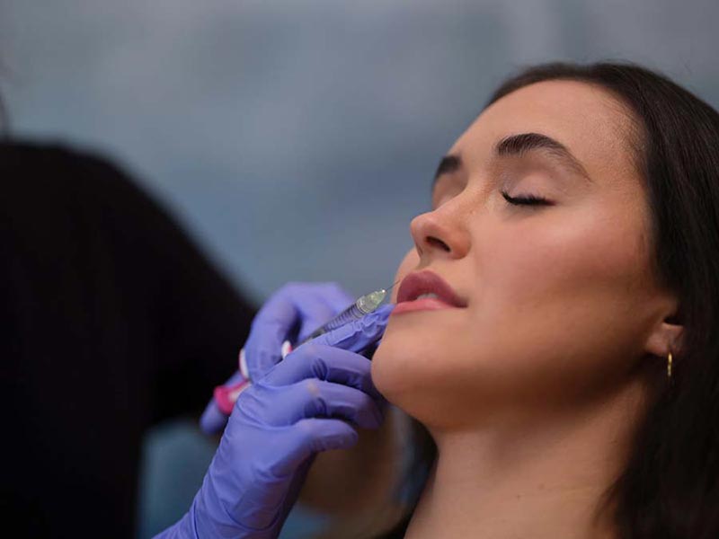 woman getting filler injection in lip